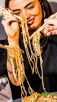 woman smiling eating noodles